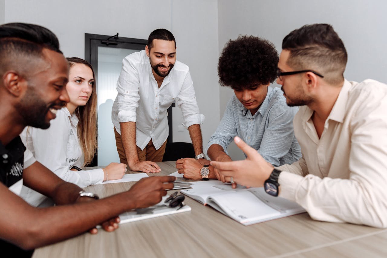 Five colleagues brainstorm around a table, focusing on project plans in a modern office environment.